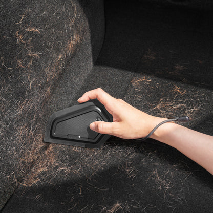 ACP11829 - Hand using the Spigen scraper to remove pet hair from a car trunk carpet