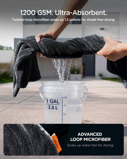 ACP11389 - Hands wringing water out of a Spigen microfiber towel over a 1-gallon bucket, demonstrating its 1200 GSM absorbency